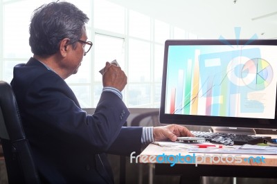 Senior Business Man Working On Office Table With Computer And Business Graph Report , Stock Photo