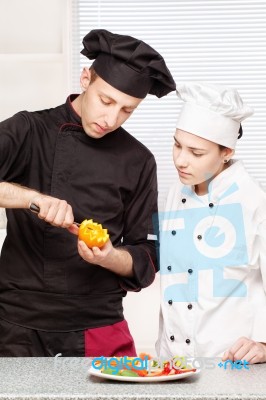 Senior Chef Teaches Young Chef To Decorate Fruit Stock Photo