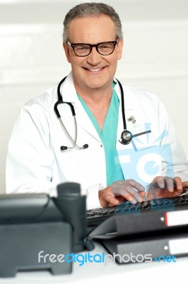Senior Doctor Typing On Keyboard Stock Photo