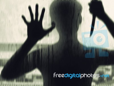 Shadowy Figure With A Knife Behind Glass Stock Photo