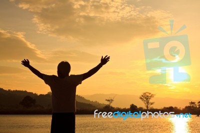 Silhouette Of Man With Hands Raised Stock Photo