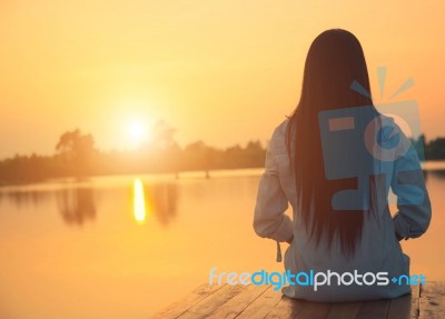 Silhouette Of Relaxing Young Woman On Wooden Pier At The Lake In Sunset Stock Photo Silhouette Of Relaxing Young Woman On Wooden Pier At The Lake In Sunset Stock Photo