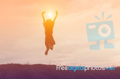 Silhouette Of Woman Jumping Against Beautiful Sky Background Stock Photo