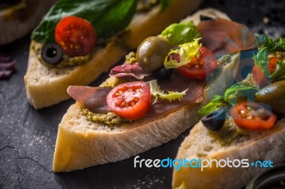 Slices Of Ciabatta With Olives , Tomatoes And Basil On The Black Stone Table Horizontal Stock Photo