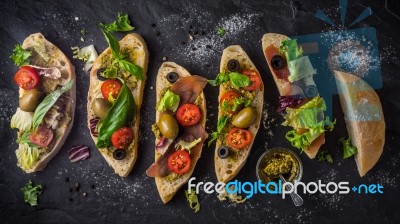 Slices Of Ciabatta With Olives , Tomatoes And Basil On The Black Stone Table Wide Screen Stock Photo