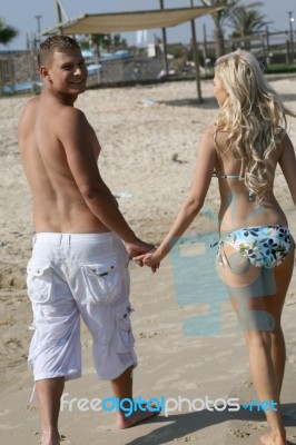 Smiling Couple Walking In Sand Stock Photo