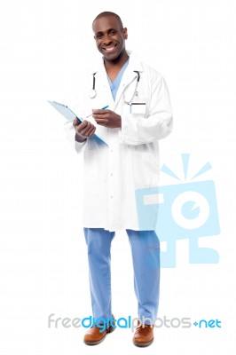 Smiling Doctor Writing On Clipboard Stock Photo