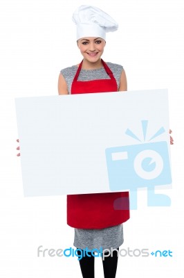 Smiling Female Chef Holding An Ad Board Stock Photo