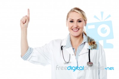 Smiling Female Doctor Pointing Upwards Stock Photo