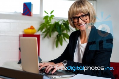 Smiling Female Manager Typing Report On Laptop Stock Photo