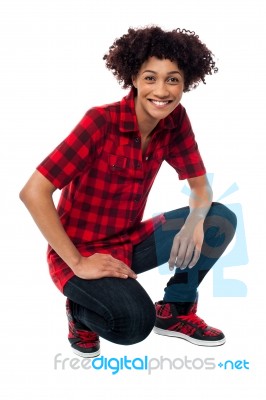 Smiling Female Model In Squatting Posture Stock Photo