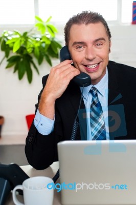 Smiling Male Manager Attending Clients Call Stock Photo