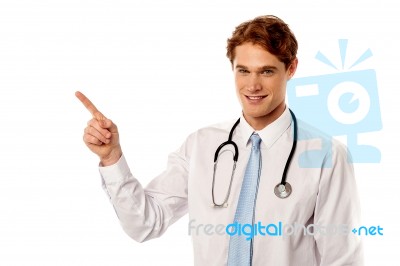 Smiling Male Physician Pointing Away Stock Photo