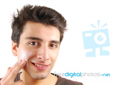 Smiling Man Applying Face Cream Stock Photo