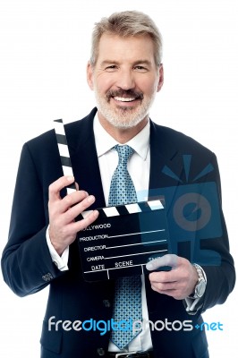 Smiling Man Showing A Clapperboard To The Camera Stock Photo