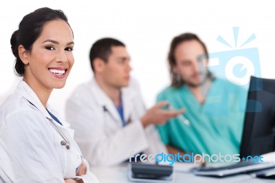 Smiling Young Doctor With Other Doctors Behind Her Stock Photo