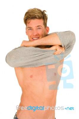 Smiling Young Man Removing T Shirt Stock Photo
