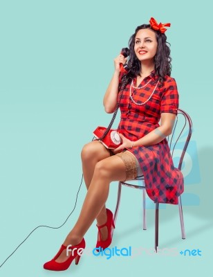 Smiling Young Pinup Woman Sitting On A Chair And Talking On Phon… Stock Photo