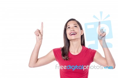 Smiling Young Woman Pointing Upwards Stock Photo