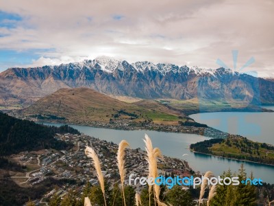 Snowy Mountain Range With A Town And Lake Stock Photo