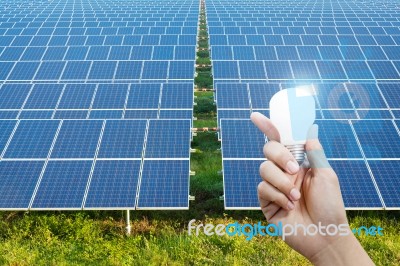 Solar Energy Panels And Light Bulb In Hand Stock Photo