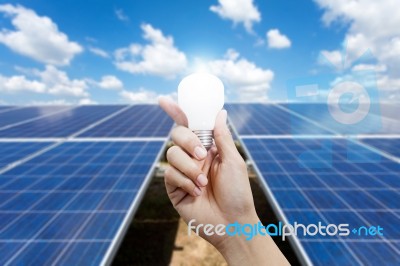 Solar Energy Panels And Light Bulb In Hand Stock Photo