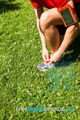 Sportsman Tying Sports Shoes On Grass Stock Photo