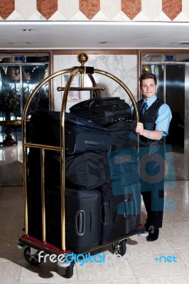 Standing Bellboy With Luggage Cart Stock Photo