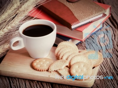 Still Life Cup Of Coffee With Cracker And Books On Wood Table Stock Photo