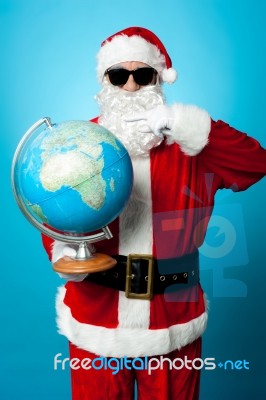 Stylish Santa In Dark Shades Pointing At The Globe Stock Photo