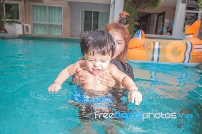 The Kid And Mom Play Together In The Pool Stock Photo