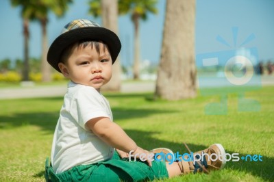 The Thai Kid Sits On The Grass Stock Photo