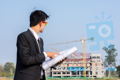The Young Businessman Holds A Blueprint And Looks At The Structu… Stock Photo