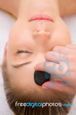 Therapist Placing Stone Woman's Forehead Stock Photo