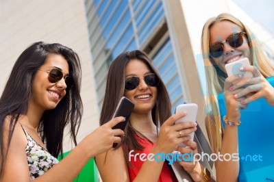 Three Girls Chatting With Their Smartphones At The Campus Stock Photo