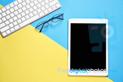 Top View, Modern Workplace With Tablet Placed On A Pastel Yellow Background. Copy Space Suitable For Use In Graphics Stock Photo