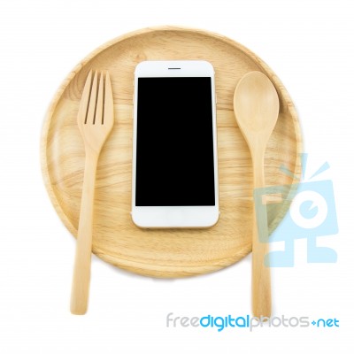 Top View Smartphone On Wooden Dish With Spon And Fork On White Background, Concept Eating Technology Stock Photo