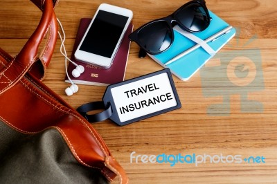 Travel Insurance Tag With Bag On Wood Background Stock Photo