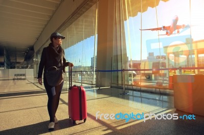 Traveling Woman And Luggage Walking In Airport Terminal And Air Plane Flying Outside Stock Photo