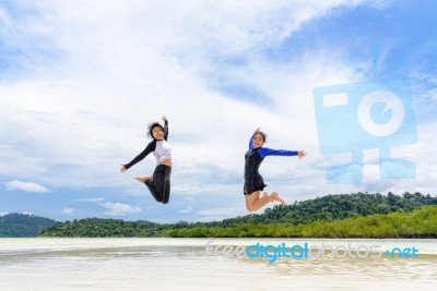 Two Asian Teen Girls Friends Jumping Enjoy On The Beach Stock Photo