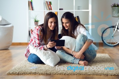 Two Beautiful Young Woman Friends Using Digital Tablet At Home Stock Photo