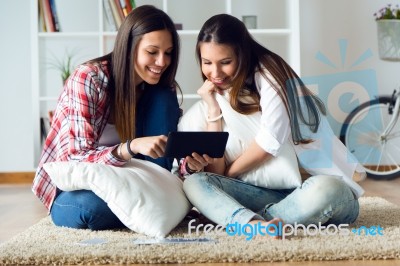 Two Beautiful Young Woman Friends Using Digital Tablet At Home Stock Photo