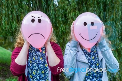 Two Girls Holding Balloons With Facial Expressions Stock Photo