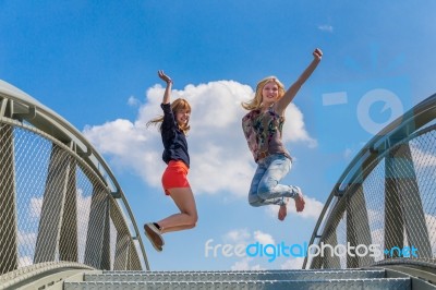 Two Happy Teenage Girls Jumping On Bridge Stock Photo