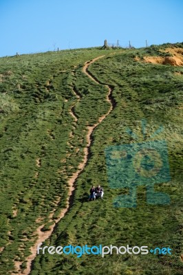 Two People Sitting Half Way Up A Cliff At Lyme Regis Stock Photo