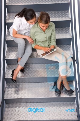 Two Women Sitting Staircase Using Digital Tablet Stock Photo