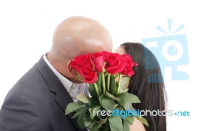 Two Young Dates Kissing Behind A Bouquet Of Red Roses Stock Photo