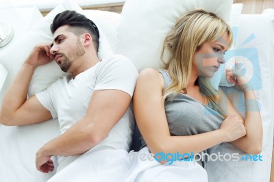 Upset Couple Lying Back To Back In Bed Stock Photo