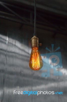 Vintage Hanging Light Bulb Over Gray Room Stock Photo