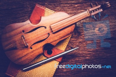 Violin And Notebook With Pen On Grunge Dark Wood Background Stock Photo
